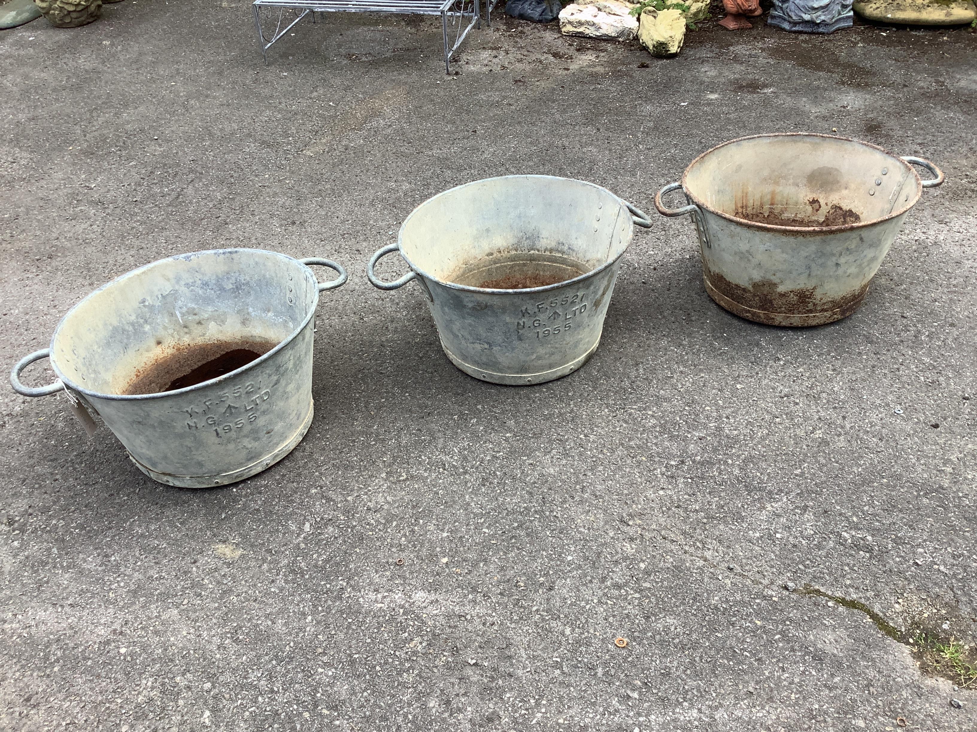 Three circular galvanised two handled containers, two marked N G Ltd., and dated 1955, diameter 49cm, height 30cm